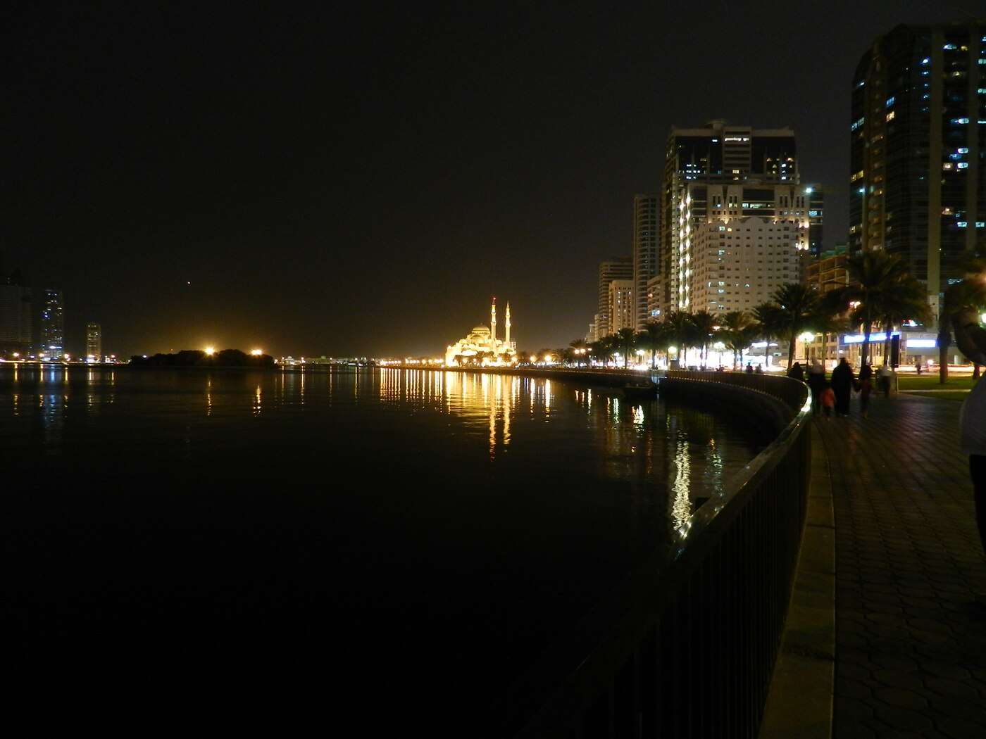 Sharjah's Khalid Lagoon corniche at night with the Al Noor Mosque lit along the water